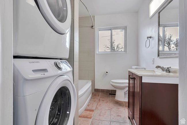Bathroom with a wealth of natural light, stacked washer and dryer, vanity, and toilet | Image 6