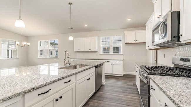 Kitchen with decorative light fixtures, white cabinetry, dark hardwood / wood-style flooring, sink, and appliances with stainless steel finishes | Image 13