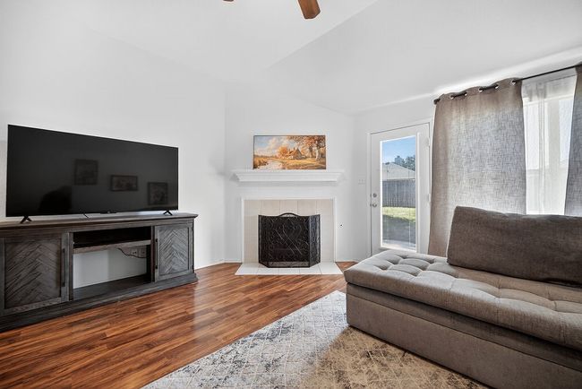 Living area featuring a tiled fireplace, lofted ceiling, wood finished floors, and ceiling fan | Image 31