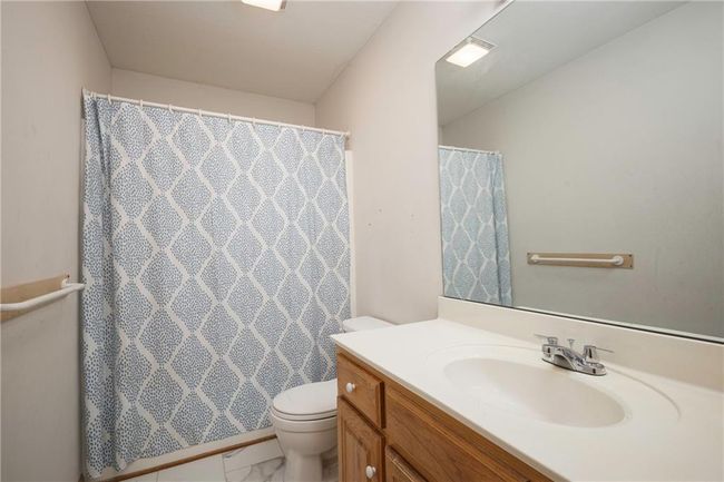 Full bathroom with vanity, toilet, a shower with curtain, and marble look tiles | Image 24