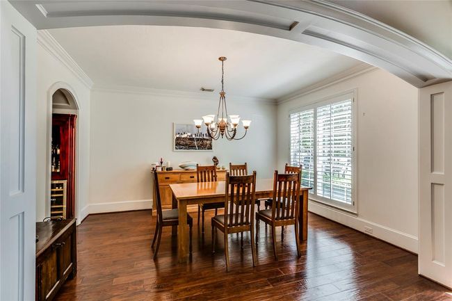 Enter this Large Dining Room with custom wooden arch, hardwood floor, plantation shutter & chandelier | Image 9