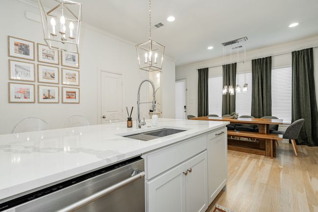 Kitchen with crown molding, a chandelier, dishwasher, a sink, and light wood finished floors | Image 11