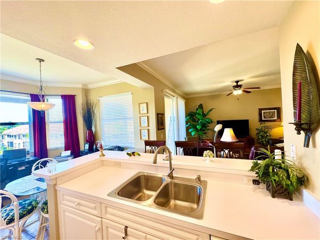 Kitchen with pendant lighting, a ceiling fan, a sink, crown molding, and light countertops | Image 11