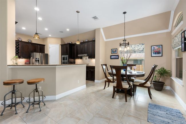 Kitchen with appliances with stainless steel finishes, decorative backsplash, a chandelier, dark brown cabinetry, and recessed lighting | Image 15