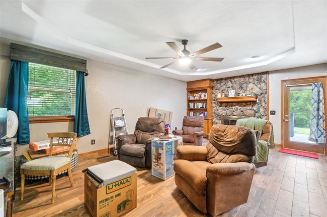 Living area with a tray ceiling, light wood-style flooring, and a ceiling fan | Image 8