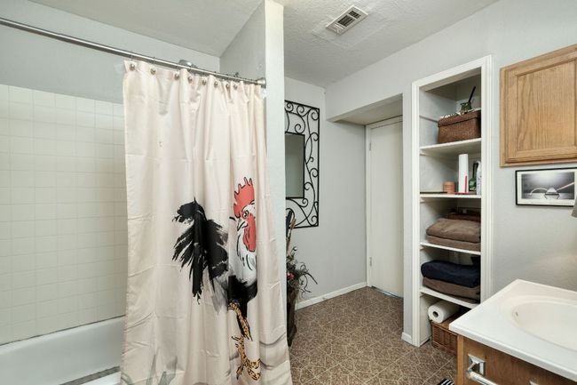 Full bath featuring shower / bath combo, tile patterned floors, vanity, and baseboards | Image 21
