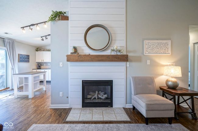 living room featuring track lighting, wood finished floors, baseboards, visible vents, and a fireplace with flush hearth | Image 9
