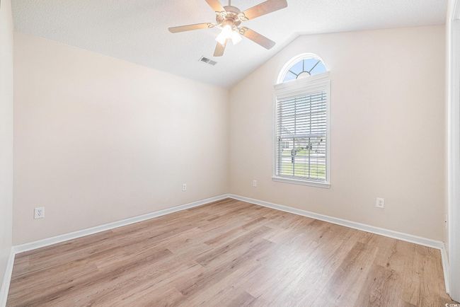 Empty room with light wood-style flooring, vaulted ceiling, and ceiling fan | Image 26