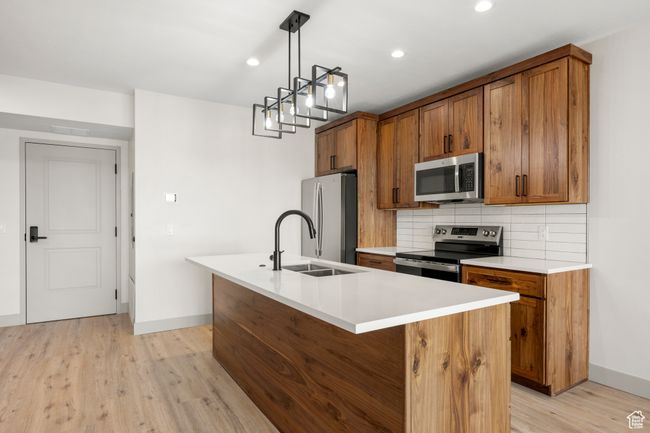 Kitchen with stainless steel appliances, brown cabinets, baseboards, a sink, and recessed lighting | Image 6