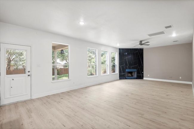 Unfurnished living room with light wood-style floors, a premium fireplace, a ceiling fan, and recessed lighting | Image 6