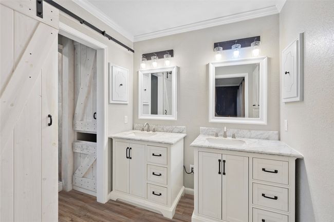 Bathroom featuring crown molding, wood finished floors, and two vanities | Image 13
