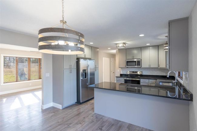 Kitchen with kitchen peninsula, appliances with stainless steel finishes, light wood-type flooring, sink, and hanging light fixtures | Image 37