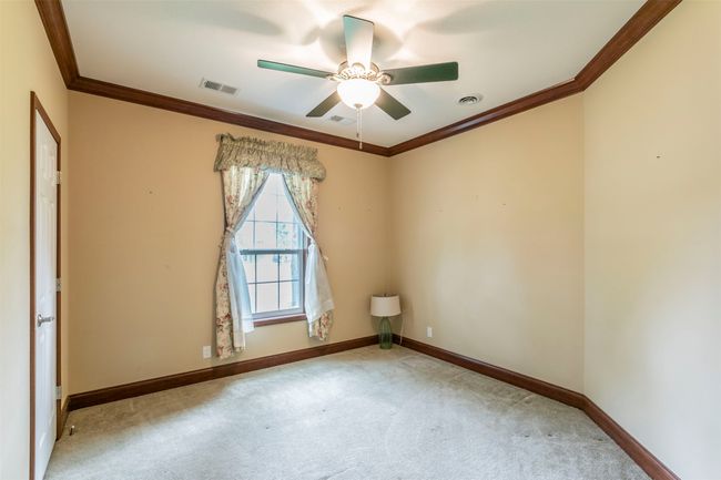 Empty room with visible vents, carpet flooring, crown molding, and a ceiling fan | Image 17