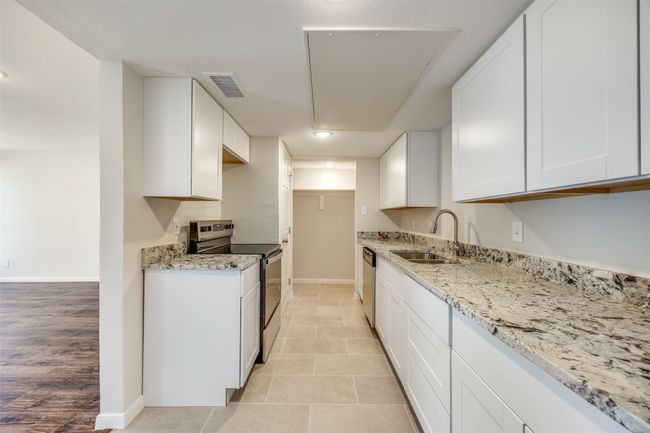 Kitchen featuring light granite countertops, stainless steel appliances, white cabinetry, and sink | Image 9