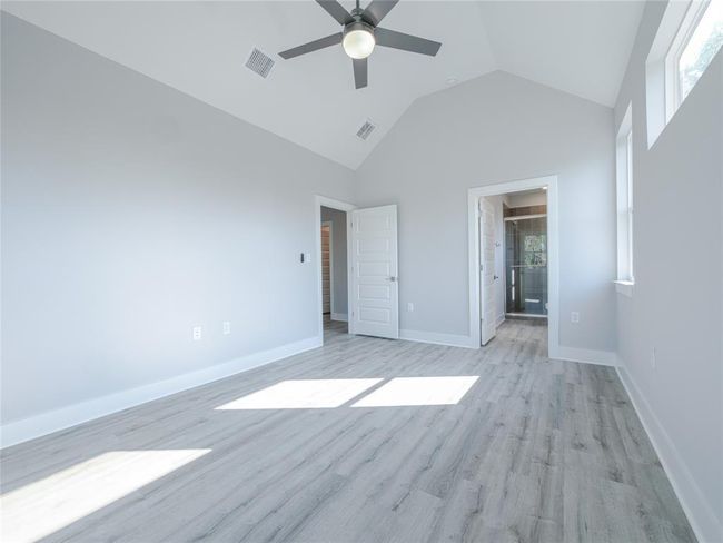 Unfurnished bedroom featuring light wood-type flooring, high vaulted ceiling, ceiling fan, and connected bathroom | Image 17