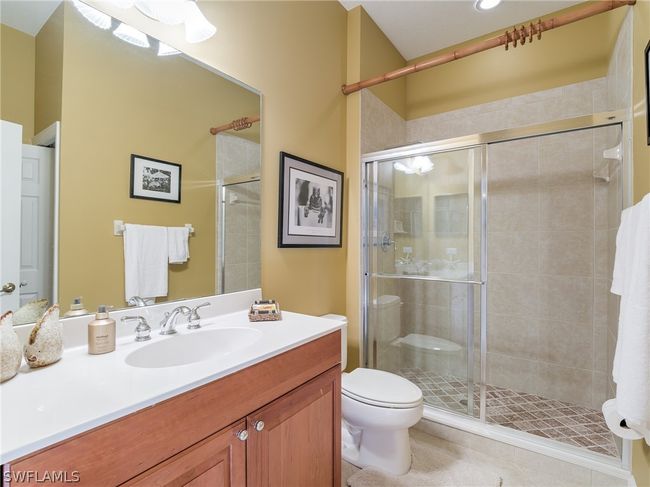 Bathroom with tile floors, a shower with door, toilet, and large vanity | Image 29