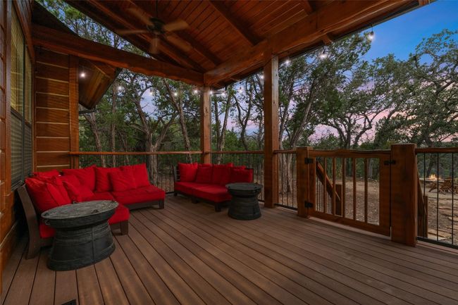 As dusk falls, this back deck becomes an inviting retreat with string lights creating a warm, intimate atmosphere. Surrounded by trees, it’s the perfect place to unwind while enjoying the natural beauty and the nearby fire pit below. | Image 21