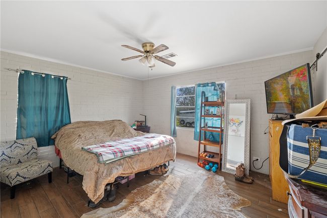 Bedroom featuring dark hardwood / wood-style floors, ceiling fan, and brick wall | Image 13