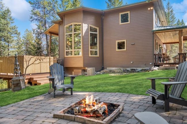 Rear view of property with recently added central AC unit, and outdoor fire pit, and a privacy fence around hot tub. | Image 15