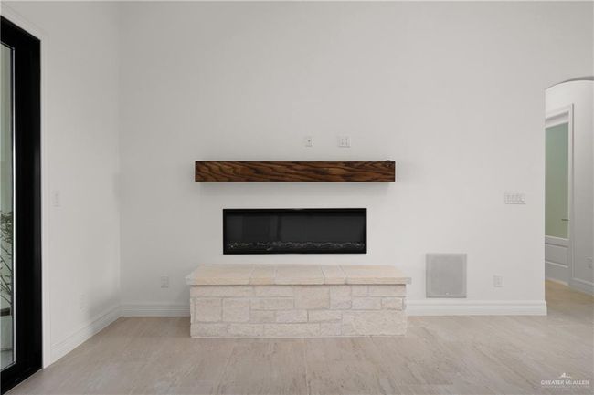 Close-up view of the sleek, modern fireplace — a perfect blend of traditional and contemporary design. This linear gas fireplace features a stacked stone base, floating wood mantel, and pre-wired connections above for effortless TV or artwork mounting. | Image 6