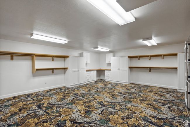 Finished basement with dark carpet, baseboards, and built in desk | Image 62