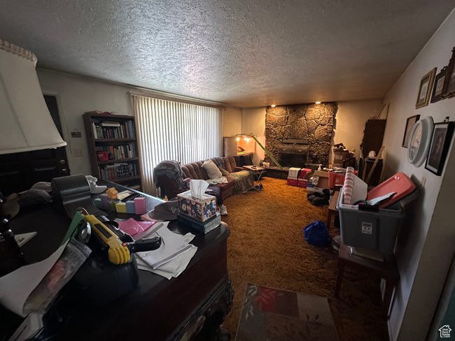 Living room with carpet flooring, a textured ceiling, and a stone fireplace | Image 10