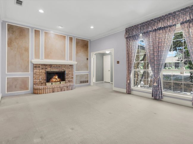 Living room features a brick gas fireplace, recessed lighting and large windows to enhance the space. | Image 8