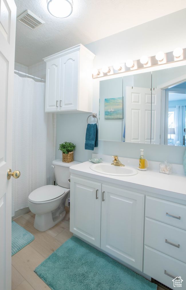 Bathroom with vanity, toilet, wood finished floors, and a textured ceiling | Image 14