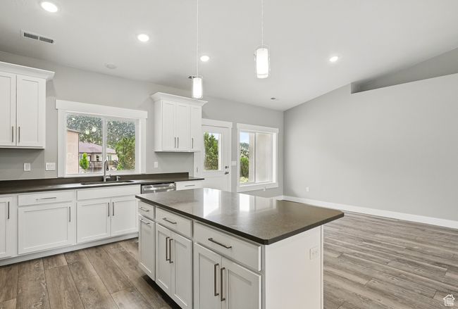 Kitchen with a sink, dark countertops, light wood-style floors, white cabinets, and vaulted ceiling | Image 20