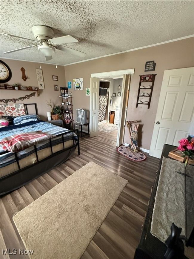 Bedroom with a ceiling fan, a textured ceiling, dark wood finished floors, baseboards, and ornamental molding | Image 23