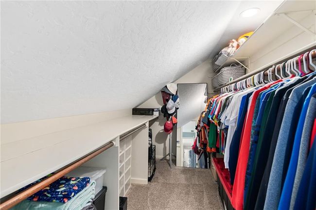 Walk in closet featuring light colored carpet and lofted ceiling | Image 25