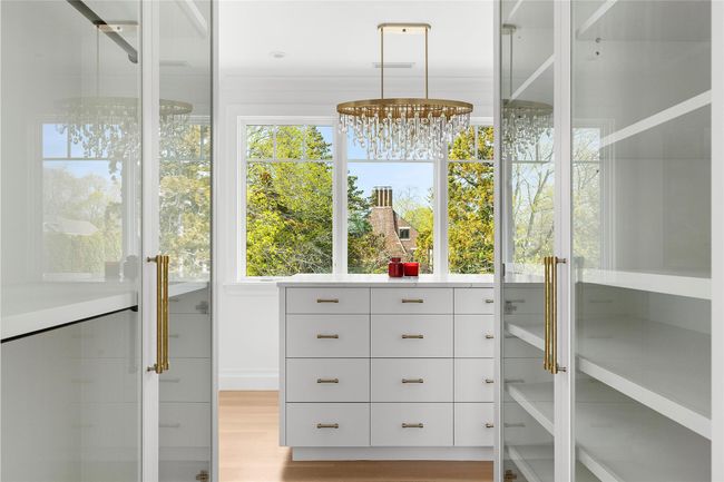 Primary Walk in closet with custom built ins, island and chandelier | Image 19