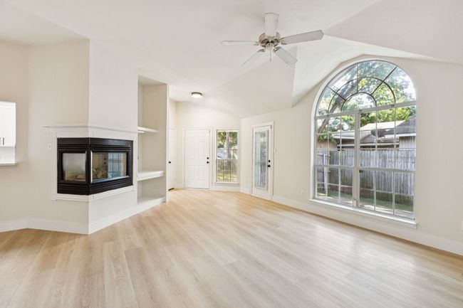 Unfurnished living room featuring light wood-style flooring, ceiling fan, a multi sided fireplace, and lofted ceiling | Image 10