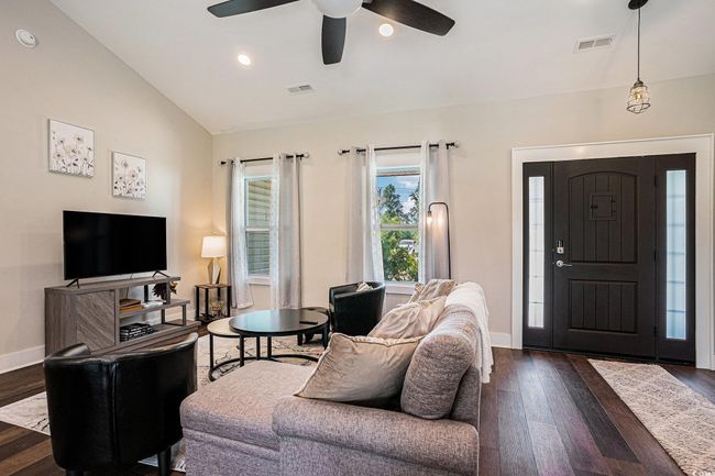 Living area with dark wood finished floors, a ceiling fan, lofted ceiling, and recessed lighting | Image 4