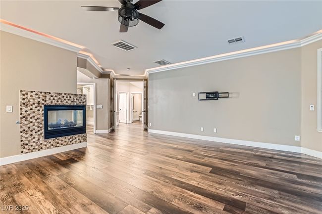 Unfurnished living room with hardwood / wood-style flooring, a ceiling fan, ornamental molding, and a fireplace | Image 20