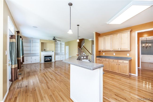 Kitchen featuring light wood-style flooring, a ceiling fan, a fireplace, open floor plan, and light brown cabinets | Image 9