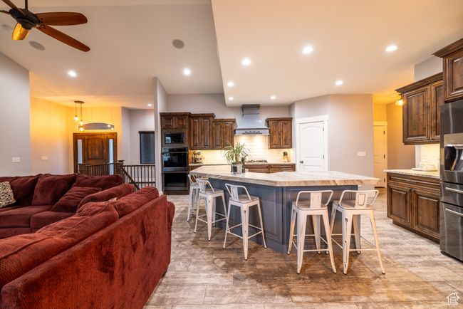 Kitchen featuring custom range hood, black appliances, open floor plan, light countertops, and a large island | Image 15
