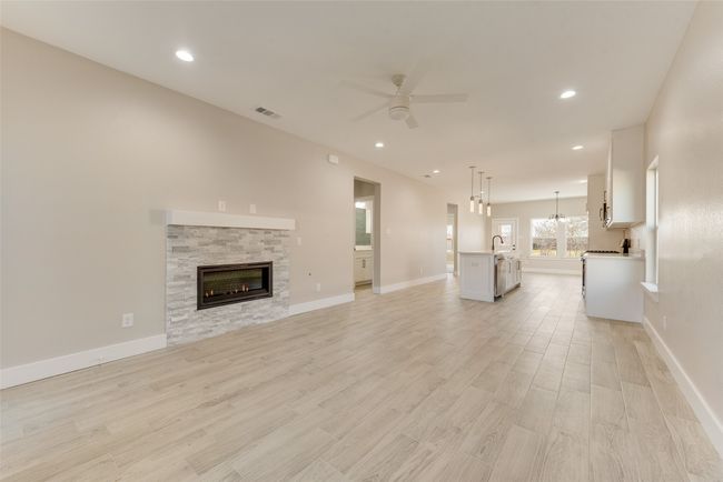 Unfurnished living room with ceiling fan, light wood-style floors, a stone fireplace, and recessed lighting | Image 7