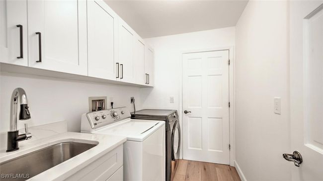 Laundry area with cabinet space, washing machine and clothes dryer, and light wood-type flooring | Image 30