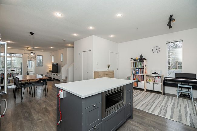 Kitchen featuring gray cabinetry, dark wood-type flooring, a kitchen island, open floor plan, and stainless steel microwave | Image 14