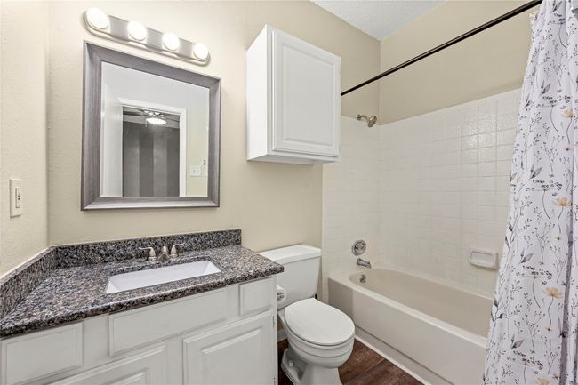 Full bath featuring toilet, shower / bathtub combination with curtain, vanity, and wood finished floors | Image 13