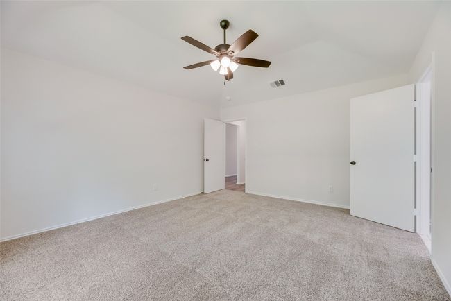Empty room with a ceiling fan, light carpet, vaulted ceiling, and baseboards | Image 12