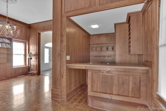 Bar featuring wooden walls, a chandelier, crown molding, and pendant lighting | Image 18