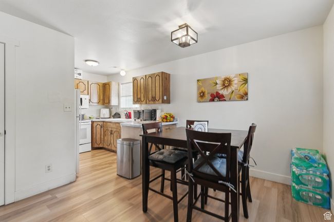 Kitchen with light wood finished floors, baseboards, white appliances, brown cabinetry, and light countertops | Image 16