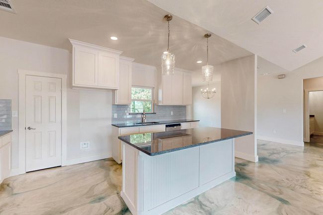 Kitchen featuring backsplash, a center island, white cabinets, a chandelier, and recessed lighting | Image 21