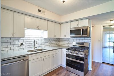 Kitchen with sink, appliances with stainless steel finishes, dark wood-type flooring, and white cabinets | Image 2