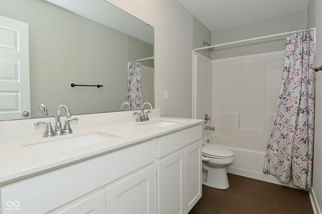bathroom with shower / tub combo with curtain, double vanity, a sink, and toilet | Image 33