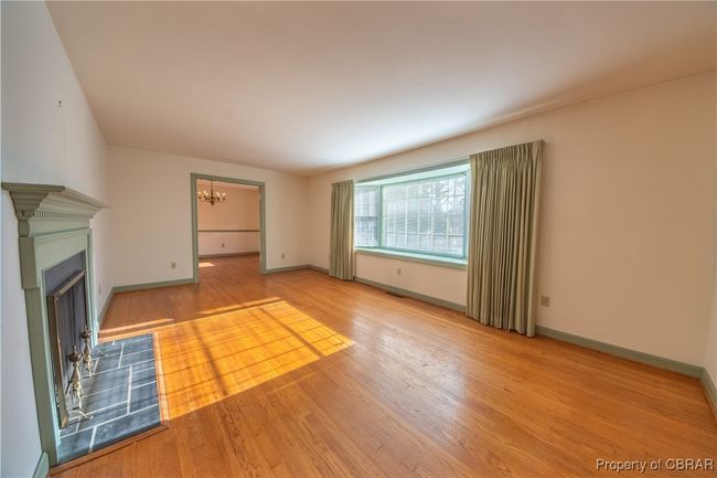 Unfurnished living room with wood-type flooring and a notable chandelier | Image 7