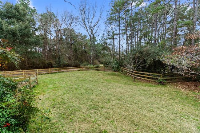 This large half-acre backyard is surrounded by a sturdy, but charming, 3 rail equestrian fence. Double fenced for reinforcement, it features wire mesh fencing to protect small dogs from escaping. This lush, green grass, as well as private nature trails, extend throughout the property and into the 15+acres of natural wilderness filled with wildlife. | Image 37