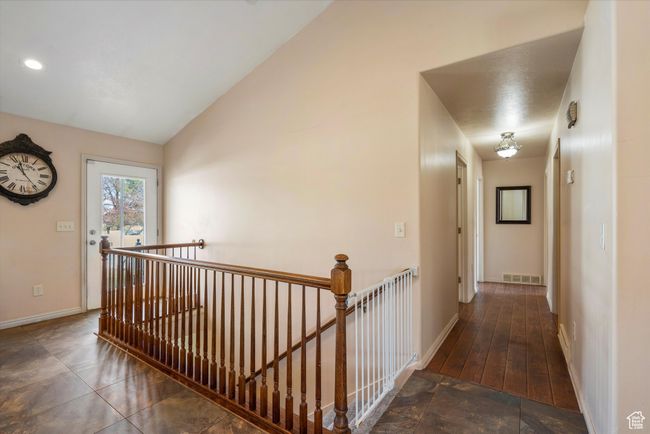Hallway with baseboards, lofted ceiling, an upstairs landing, and visible vents | Image 14